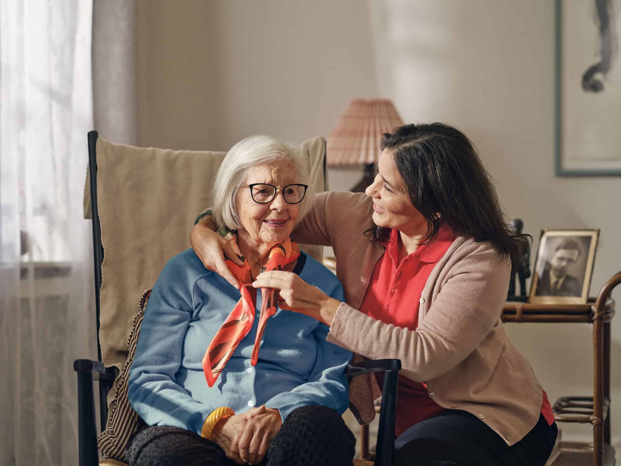 Caregiver helps client to tie her scarf