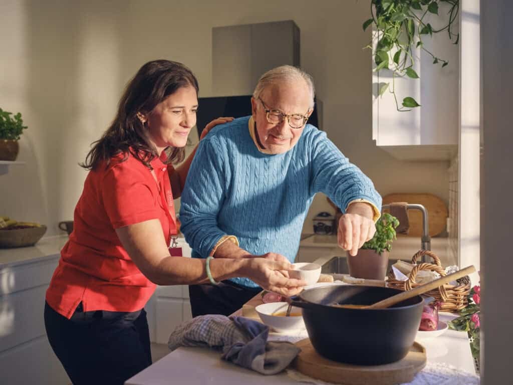 Older man and caregiver preparing a meal together, illustrating the benefits of Live-in Care.